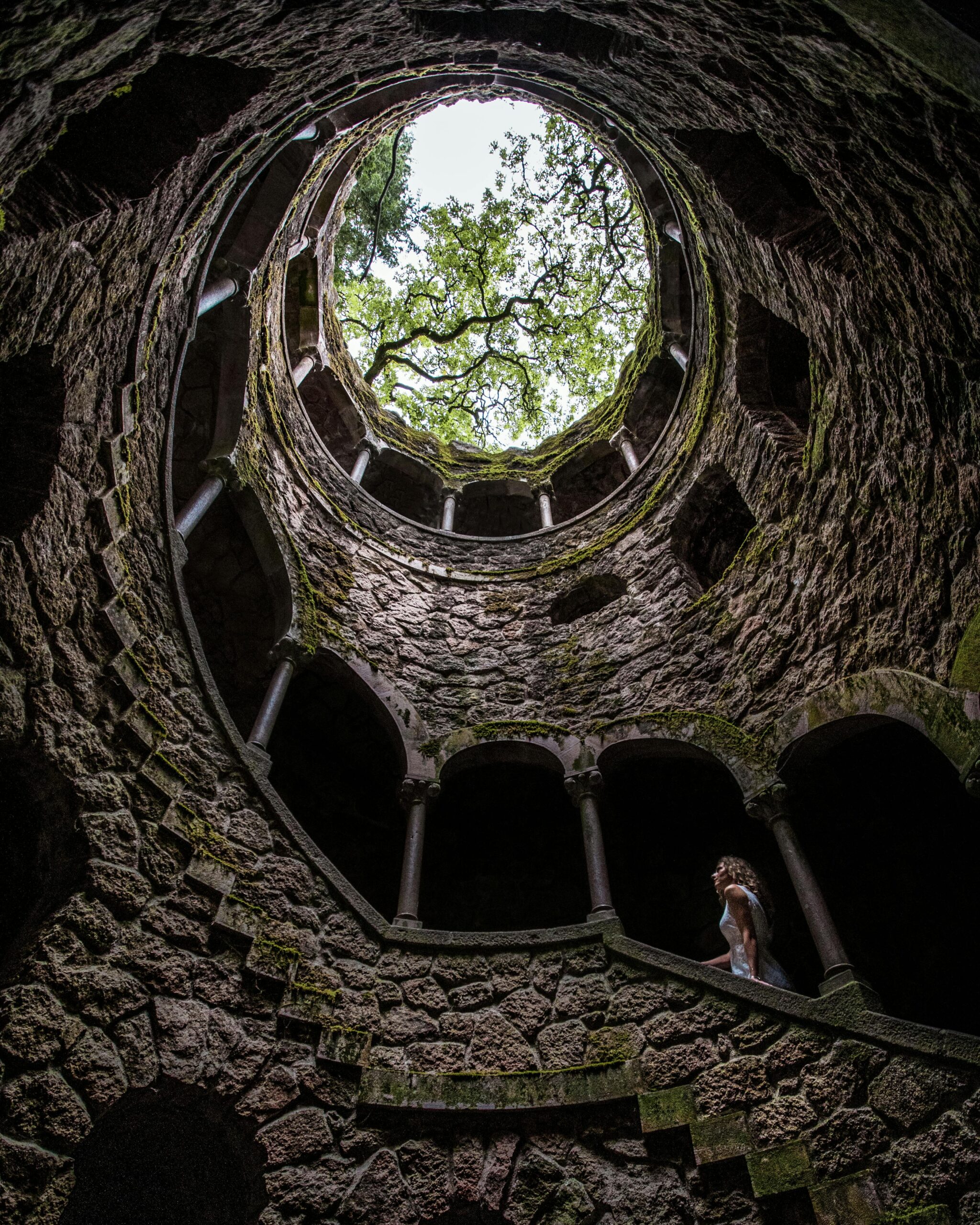 A woman spiraling upward through an ancient stone tower toward light